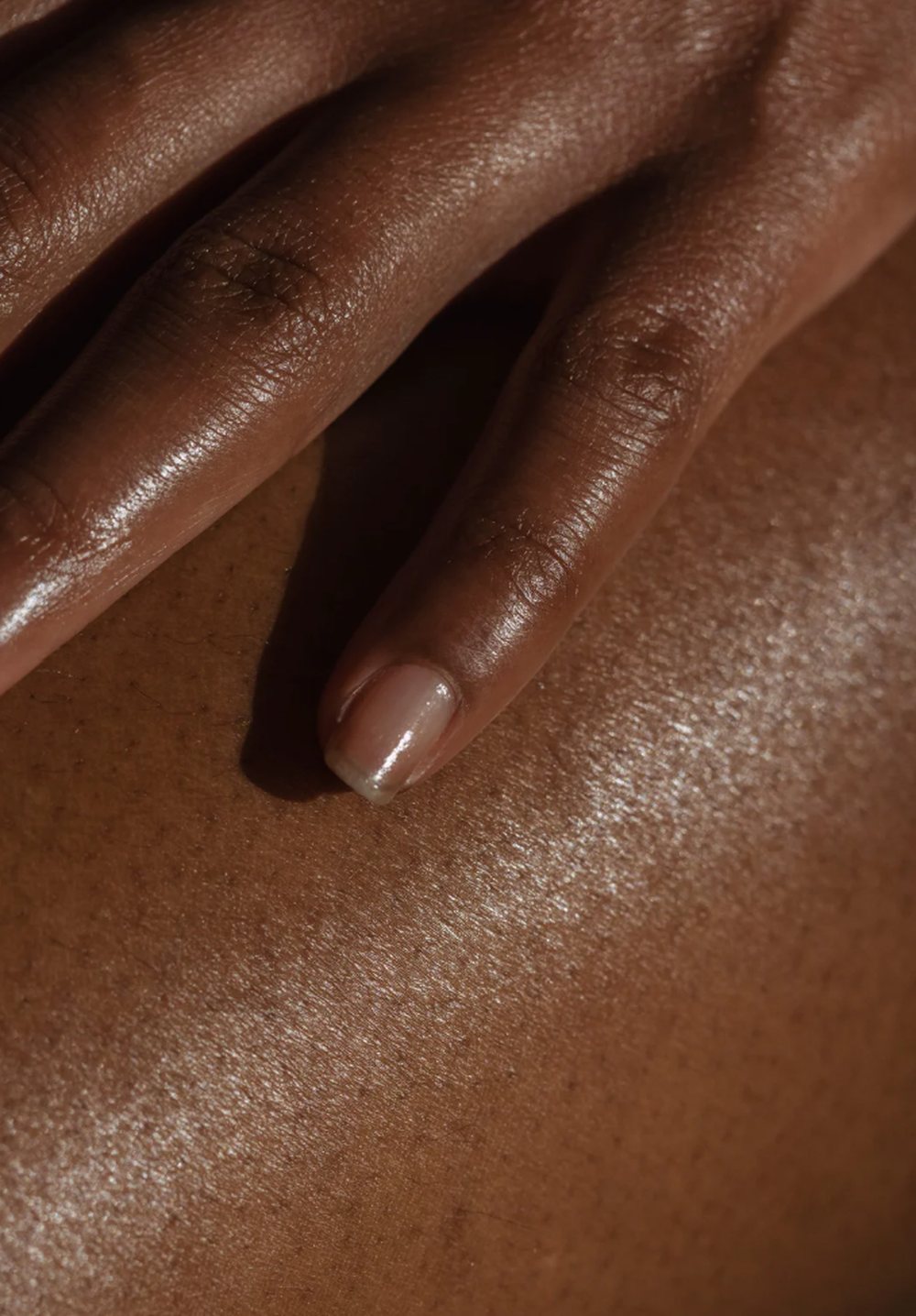 Hand resting on skin in warm low light